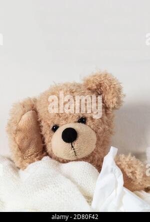 Raffreddore, influenza o allergia nei bambini. Cute teddy in letto che tiene un tessuto e coperto con una coperta calda. Sintomi del coronavirus nei bambini Foto Stock