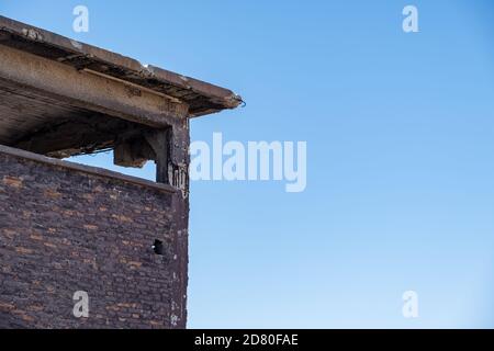 Parte della vecchia fabbrica di fertilizzanti abbandonata mattoni e pietra edificio facciata rovine a Drapetsona Pireo Grecia, cielo blu, giorno di sole. Industriale storico Foto Stock