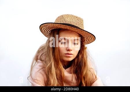 Ritratto di una bella ragazza adolescente in un cappello di paglia contro il cielo che guarda verso il basso. Foto Stock