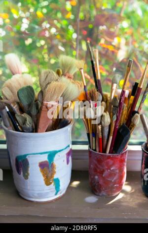 artisti pennelli in contenitori su un davanzale della finestra Foto Stock