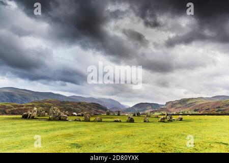 Inghilterra. Questo è l'autunno nel Lake District e una vista alternativa al Castello Rigg Druid cerchio di pietra vicino a Keswick e drammatiche nubi tempesta Foto Stock