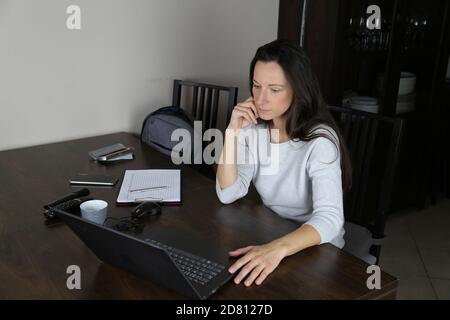 La donna lavora a casa su un computer portatile Foto Stock
