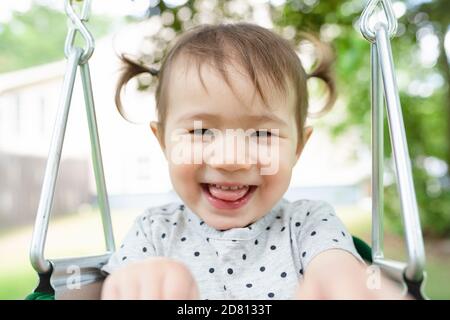 Primo piano di adorabile ragazza toddler sorridente in Backyard Swing Foto Stock