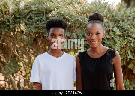 Bella mamma afroamericana all'aperto con il figlio del presteen sorridente Foto Stock