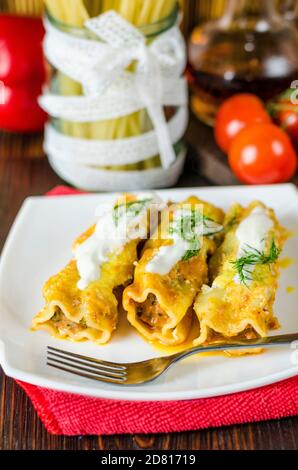 Cannelloni con ripieno di carne in salsa di panna su a. piastra Foto Stock