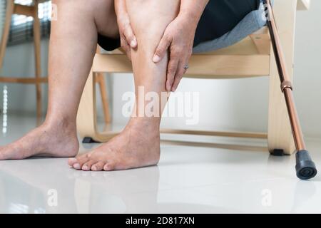 Dolore alle gambe della donna anziana a casa, problema sanitario di concetto senior Foto Stock