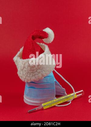 Cappello Babbo Natale con maschera facciale e termometro clinico Foto Stock