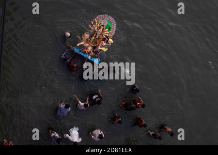 NOTA DEL REDATTORE ( immagine presa con un drone) i devoti indù sommergono un idolo della dea indù Durga sul fiume Buriganga durante l'ultimo giorno del festival di Durga Puja. Il Durga Festival di quattro giorni è celebrato in tutto il Bangladesh e culmina nell'immersione degli idoli della dea indù Durga per simboleggiare il potere e il trionfo del bene sul male nella mitologia indù. Foto Stock