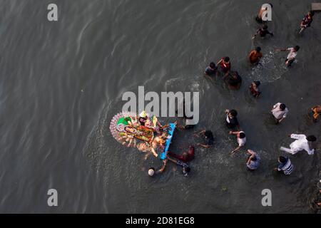 NOTA DEL REDATTORE ( immagine presa con un drone) i devoti indù sommergono un idolo della dea indù Durga sul fiume Buriganga durante l'ultimo giorno del festival di Durga Puja. Il Durga Festival di quattro giorni è celebrato in tutto il Bangladesh e culmina nell'immersione degli idoli della dea indù Durga per simboleggiare il potere e il trionfo del bene sul male nella mitologia indù. Foto Stock