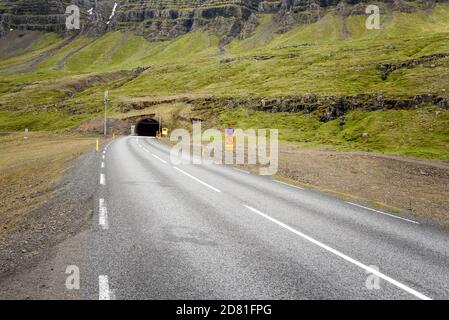 Strada che va in un tunnel sotto una montagna in Islanda in primavera Foto Stock