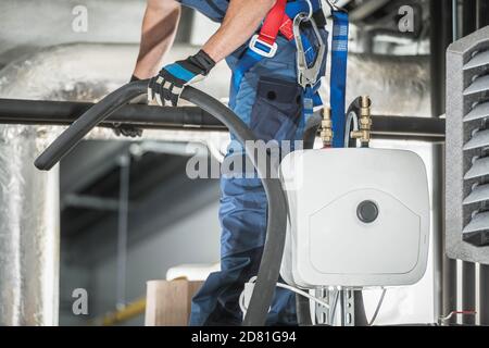 Installatore tecnico caucasico per le tecnologie di riscaldamento e raffreddamento HVAC nei suoi 40 anni all'interno del magazzino costruire l'intera nuova infrastruttura. Foto Stock