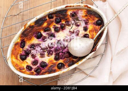 Delicata casseruola di cagliata con uva in ceramica su una superficie di legno. Foto Stock