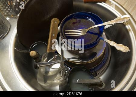 Un mucchio di piatti sporchi non lavati nel lavandino nella cucina o sala da pranzo. Lavoro a casa per una casalinga. Ci sono piatti sporchi, tazze, tazze, cucchiai, fo Foto Stock