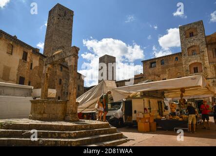 Piazza della Cisterna nel centro storico di San Gimignano, patrimonio mondiale dell'UNESCO Sito, con Torre Becci, Cugnanesi e Ardinghelli in una giornata di mercato, Toscana, Italia Foto Stock