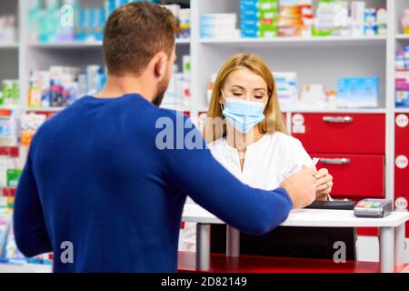 farmacista professionale femmina aiutare il cliente maschile scelta farmaci da prescrizione, consultare i clienti malati. shopping in farmacia, prendendo consiglio da giovane chimico. Consumismo, personale cordiale Foto Stock