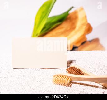 Cosmetologia biglietto da visita mock up con spazzolini da denti di bambù. Stile eco-naturale. Cemento e foglia verde. Scheda clinica di bellezza Foto Stock