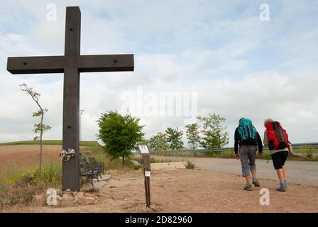 Un paio di pellegrini che passano accanto ad una croce, conosciuta come Cruz de los Valientes, nella provincia spagnola di la Rioja, sul Camino de Santiago Francés. Foto Stock