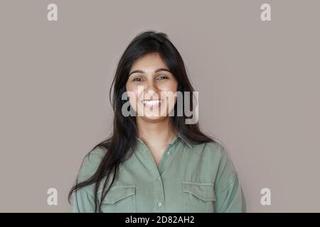 Sorridente giovane donna indiana ridente isolata su sfondo marrone. Foto Stock