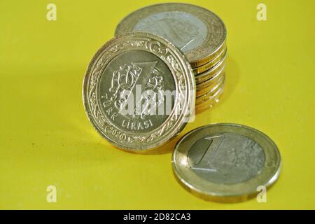 Denaro e valuta della Turchia. Denaro e gruppi di `una lira turca` monete insieme e 1 euro moneta. Sfondo isolato. Foto Stock