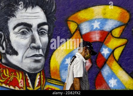 Valencia, Carabobo, Venezuela. 26 Ottobre 2020. Didascalia: 26 ottobre 2020. Un uomo, indossando una maschera anticoviale, cammina di fronte a un graffito del Liberatore, Simon Bolivar . Simon Bolivar ha liberato 5 nazioni sudamericane dal giogo spagnolo, dalla sua patria Venezuela, Colombia, Perù, Ecuador e Bolivia.questo è un tributo dall'Ufficio del Sindaco di Valencia, Carabobo, Venezuela - Foto: Juan Carlos Hernandez Credit: Juan Carlos Hernandez/ZUMA Wire/Alamy Live News Foto Stock