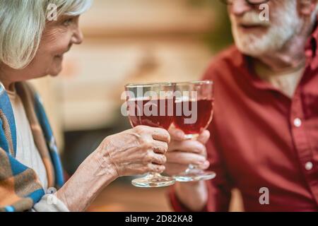 Foto ritagliata di un uomo e di una donna sorridenti che si siedono all'aperto mentre si aggrappano i bicchieri da vino. Relazione e concetto di famiglia Foto Stock