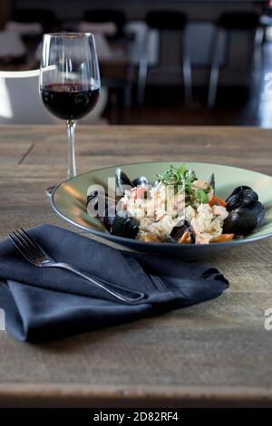 Risotto di pesce servito con cozze, gamberi e vino Foto Stock