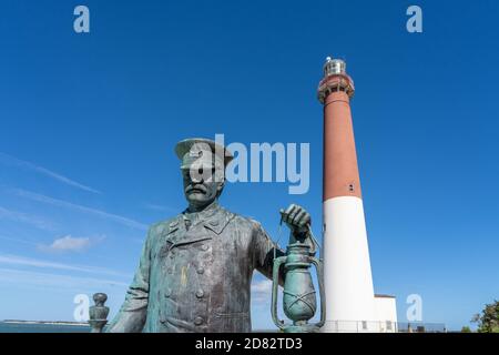 Barnegat Light, NJ - 15 ottobre 2020: Statua in bronzo intitolata 'Lighthouse Keeper' di Brian Hanlon al Barnegat Lighthouse state Park con il faro Foto Stock
