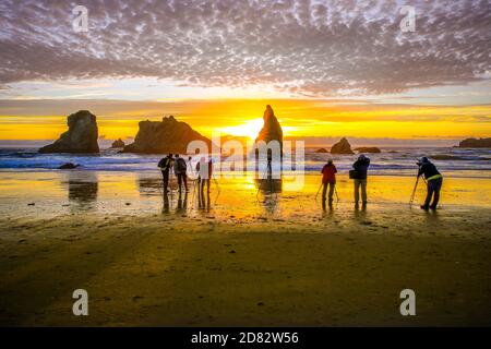 Gruppo di fotografi che scattano foto delle formazioni rocciose e del tramonto a Bandon Beach, Oregon-USA Foto Stock