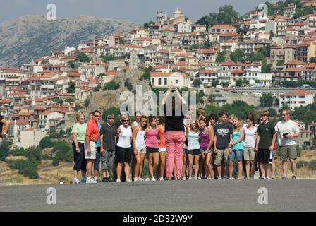 Arachova, Grecia - 27 luglio 2009: Un gruppo di scuole turistiche posa per una foto; sullo sfondo il villaggio di Arachova in Grecia (il villaggio è sfocato Foto Stock