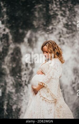 Si aspetta che la mamma indossa un abito che guarda giù alla pancia fuori dentro inverno Foto Stock