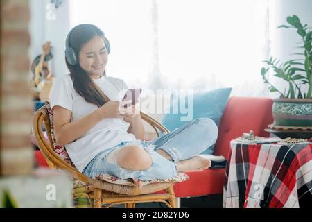 Tempo libero quarantena. Giovane donna che ascolta la musica mentre si siede sul divano in camera. Foto Stock