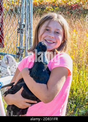 La ragazza sorridente tiene la sua anatra animale domestico mentre posa all'aperto con il suo animale Foto Stock
