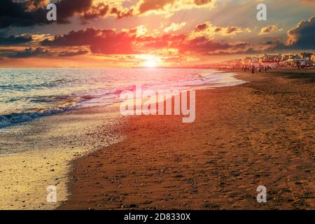 Tramonto al crepuscolo. Spiaggia di sabbia mediterranea del Lido di Ostia in serata con bel sole vicino all'orizzonte dell'acqua. Foto Stock