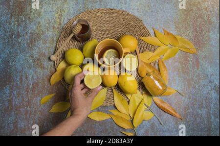 Mano umana raccogliendo mezzo limone, vita morta di limoni, curcuma e miele Foto Stock