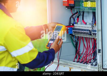 Gli operatori utilizzano il multimetro per misurare la tensione dei fili elettrici prodotti dall'energia solare per confermare il normale funzionamento dei sistemi. Foto Stock