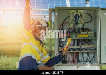 Gli operatori utilizzano il multimetro per misurare la tensione dei fili elettrici prodotti dall'energia solare per confermare il normale funzionamento dei sistemi. Foto Stock