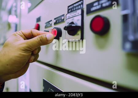 Ingegnere maschile che indossa una uniforme gialla e indossa un cappello di sicurezza bianco, ispezionando i sistemi elettrici in una grande centrale elettrica. Foto Stock