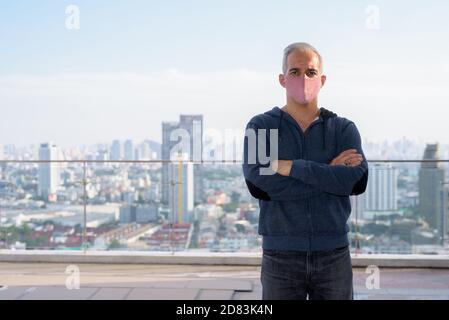 Uomo persiano che indossa una maschera con le braccia incrociate contro la vista di la città Foto Stock