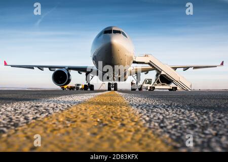 Vista frontale dell'aereo passeggeri e delle scale di imbarco presso il aeroporto grembiule Foto Stock