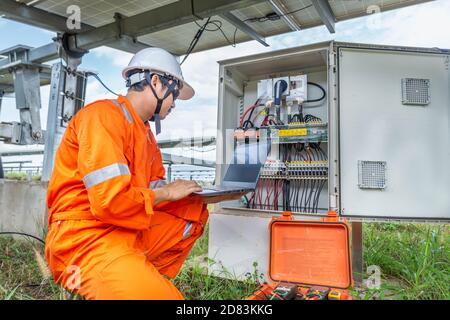 I tecnici caricano i dati dell'energia elettrica su un computer portatile per controllare le prestazioni del pannello solare e confermare il normale funzionamento dei sistemi. Concetti pro Foto Stock