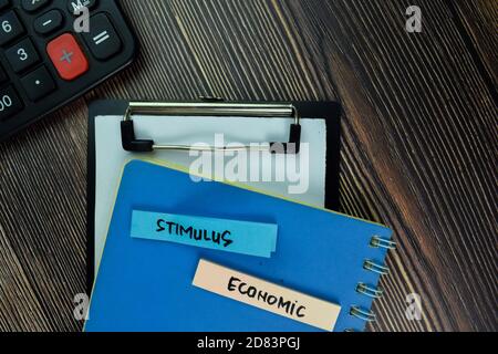 Stimolo e scrittura economica su nota appiccicosa e isolato su tavola di legno. Concetto finanziario Foto Stock