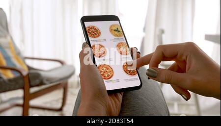 Donna che ordina la pizza a casa online Foto Stock