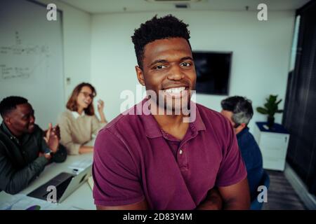 Ritratto di giovane razza mista maschio sorridente fiducioso prima della presentazione di fronte ai colleghi nella sala riunioni Foto Stock
