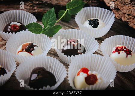Tartufi artigianali di cioccolato su sfondo ligneo. Cioccolatini fatti a mano con frutta secca. Foto Stock