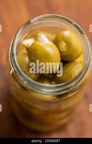 Olive verdi snocciolate farcite con mandorle in vaso su tavolo di legno. Foto Stock