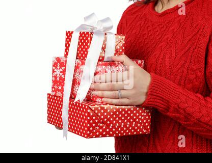 Giovane donna in pullover rosso che tiene le scatole del regalo nelle mani isolato su primo piano bianco Foto Stock