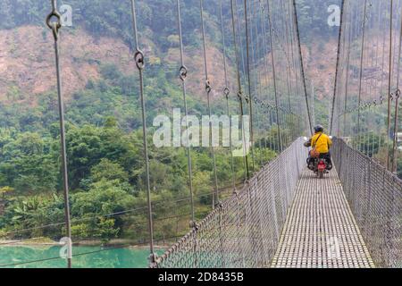 Moto che attraversa il ponte sospeso sul fiume Trishuli in Nepal Foto Stock