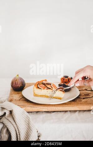 Mano di donna che mangia cheesecake di fichi senza glutine Foto Stock