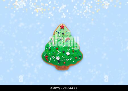 Pan di zenzero sotto forma di albero di Natale su sfondo blu. Albero di Natale creativo. Concetto di Natale minimalista. Disposizione piatta. Spazio di copia. Foto Stock