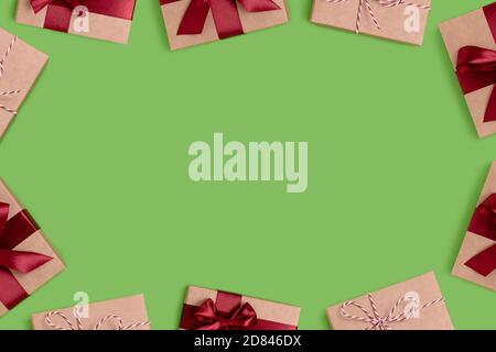 Cornice composta da scatole regalo legate con nastri rossi su sfondo verde con spazio per la copia. Concetto di festa. Foto Stock